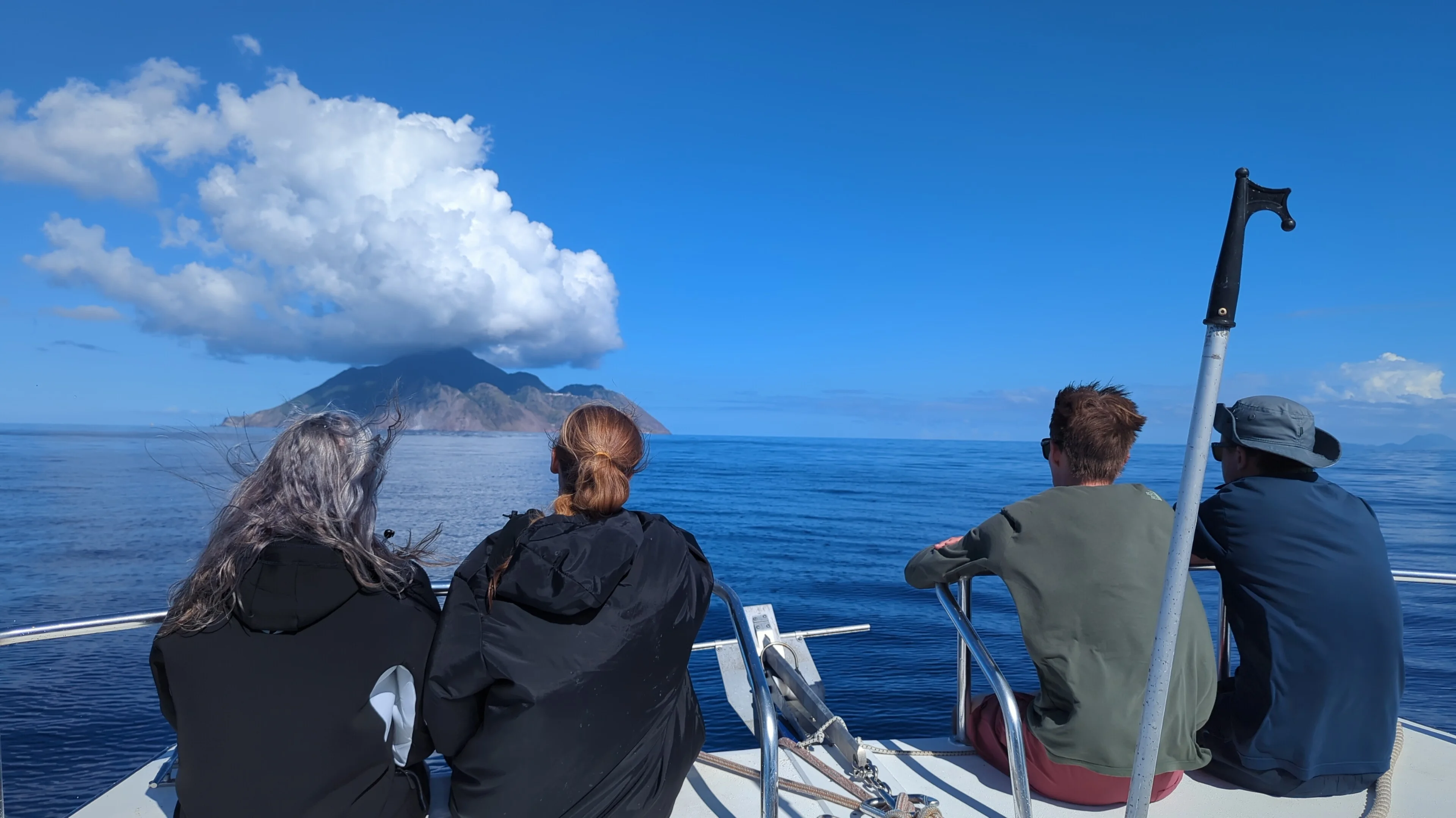 Guests sitting on the bow of a Sea Saba boat looking at Saba island.